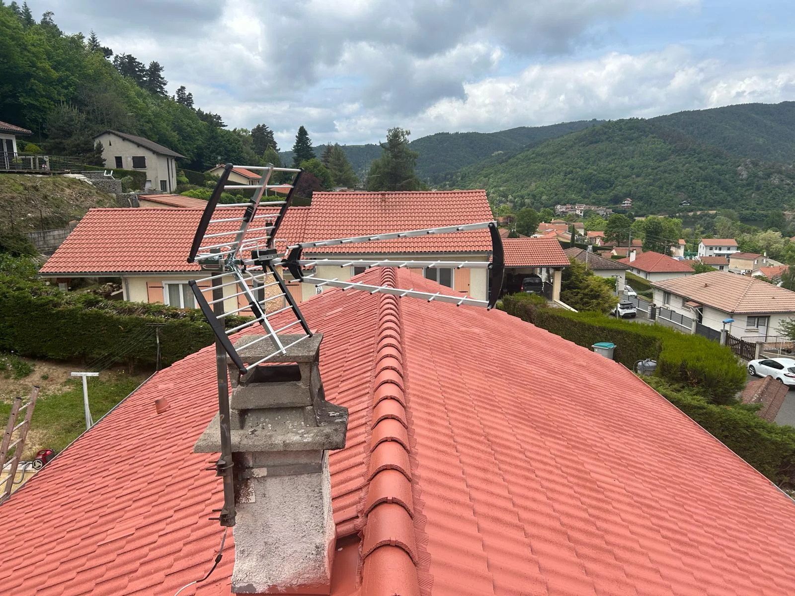 Toiture en tuiles rouges d’aspect plus uniforme, avec cheminée et antenne